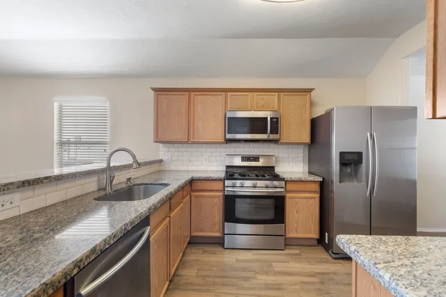 a kitchen with stainless steel appliances granite countertop a sink stove and refrigerator