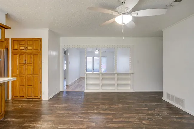 an empty room with wooden floor fan and windows