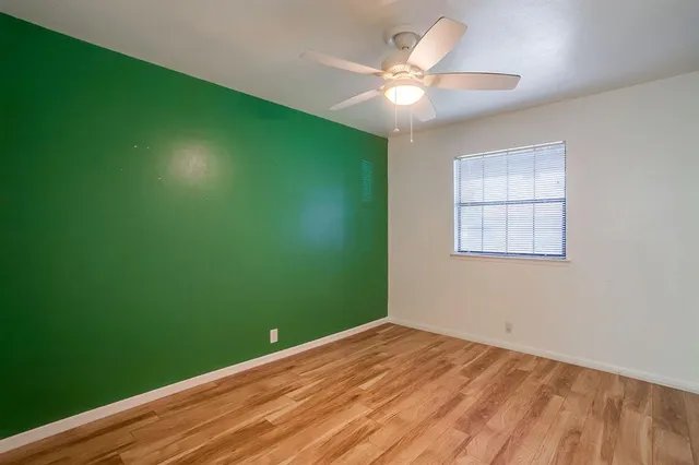 an empty room with a window and ceiling fan