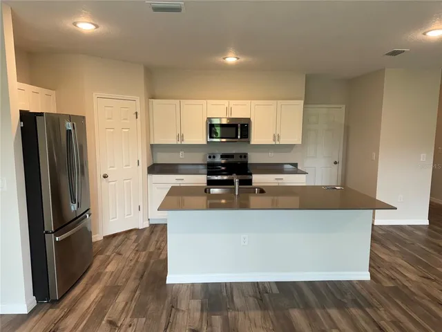 a large kitchen with stainless steel appliances a refrigerator a stove top oven a sink and dishwasher