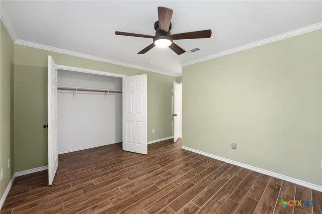 an empty room with wooden floor a ceiling fan and closet