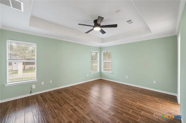 an empty room with wooden floor and a ceiling fan