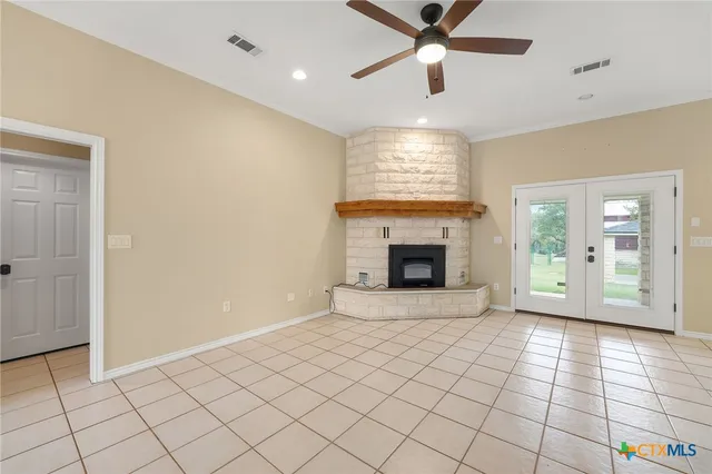 a view of an empty room with window chandelier fan and fire place