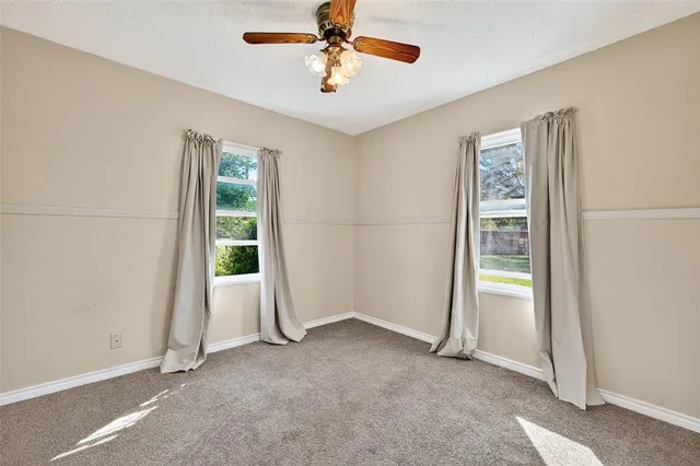 an empty room with windows and fan