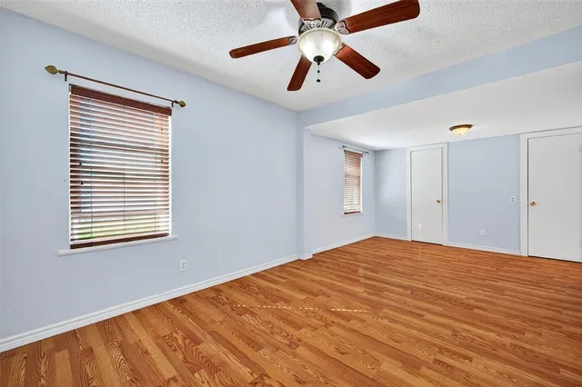 a view of empty room with wooden floor and fan