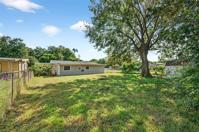 a backyard of a house with plants and large tree