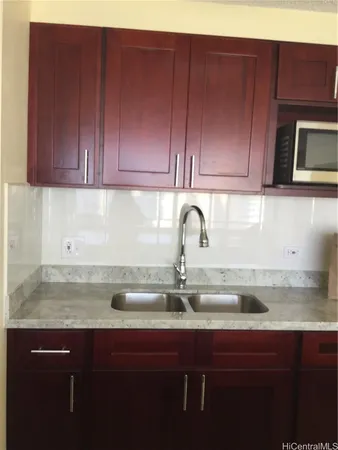 a kitchen with a sink wooden cabinets and a granite counter top