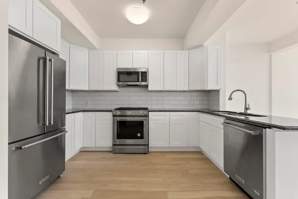 a kitchen with stainless steel appliances white cabinets white stove a microwave and a refrigerator