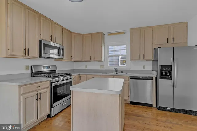 a kitchen with stainless steel appliances granite countertop white cabinets a sink a stove a refrigerator and white cabinets