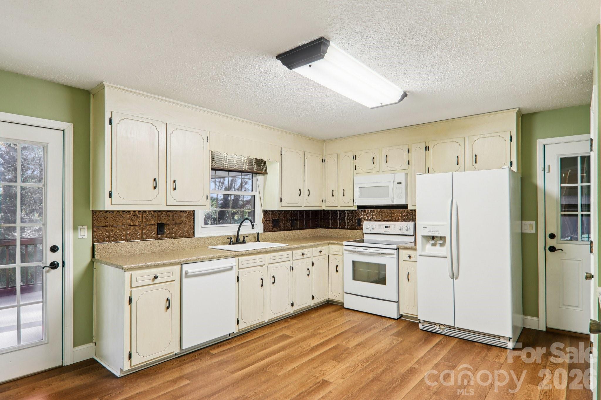 261 Eastview Road Brevard, NC 28712 - Photo 13 of 15 a kitchen with white cabinets and white appliances