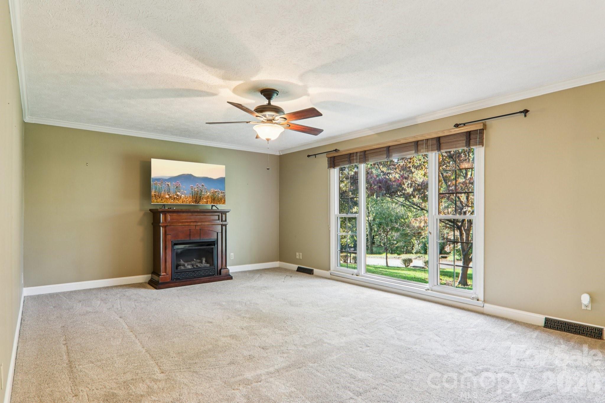 261 Eastview Road Brevard, NC 28712 - Photo 6 of 15 a view of an empty room with a fireplace and a window