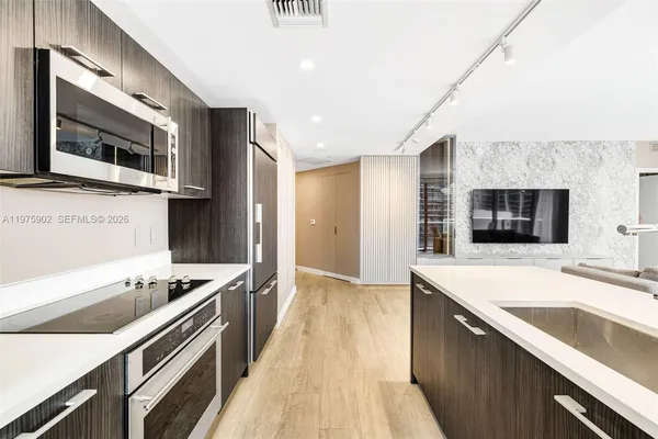 a kitchen with stainless steel appliances kitchen island granite countertop a sink and a stove top oven with wooden floor