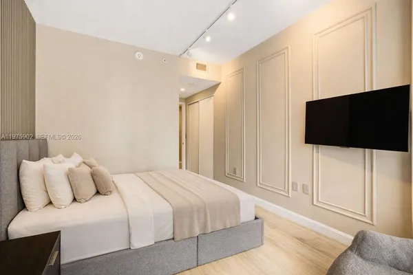 a bedroom with a bed a tv and wooden floor