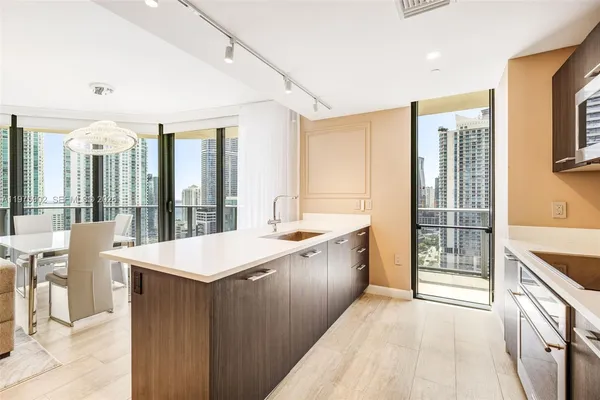 a large kitchen with kitchen island a large window a sink and stainless steel appliances