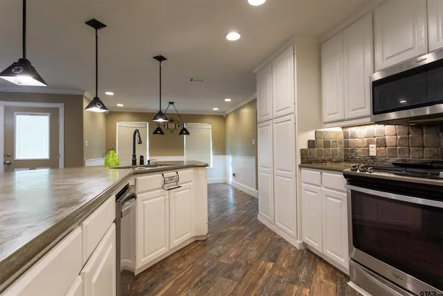 a kitchen with stainless steel appliances granite countertop a sink a stove and a refrigerator