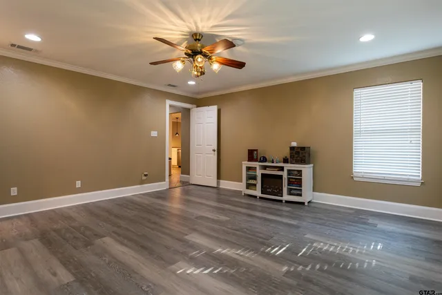 an empty room with wooden floor ceiling fan and windows