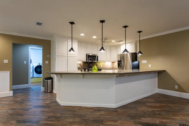 a kitchen with stainless steel appliances granite countertop a sink a refrigerator and a wooden floors