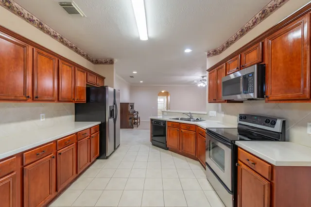 a kitchen with stainless steel appliances granite countertop wooden cabinets a stove top oven a sink and dishwasher