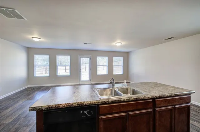 a kitchen with granite countertop a sink a counter space and windows