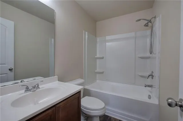 a bathroom with a bathtub shower sink vanity mirror and toilet