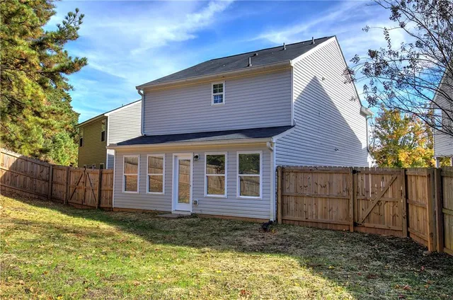 a brick house that has a small yard and large trees