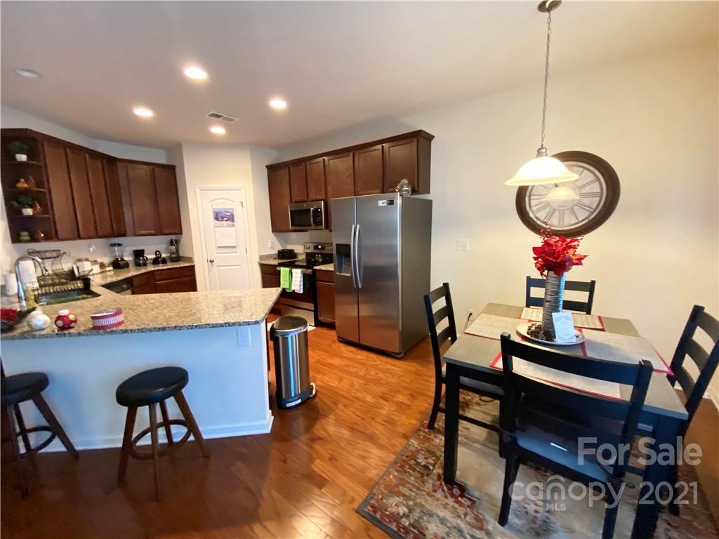 6339 Prosperity Church Road Charlotte, NC 28269 - Photo 9 of 21 a kitchen with stainless steel appliances granite countertop a dining table chairs refrigerator and cabinets
