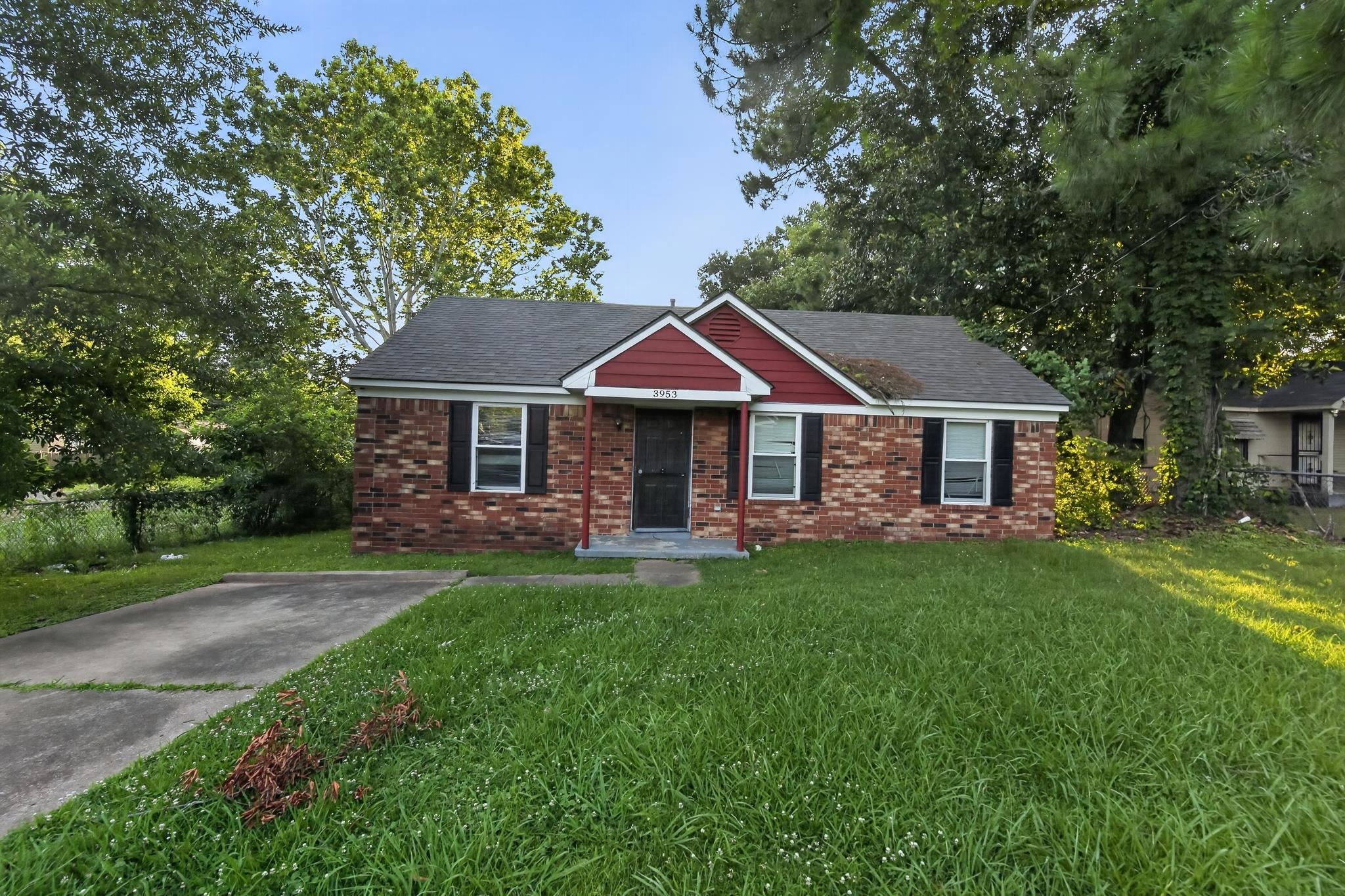 Brick ranch-style residence featuring a prominent red gable accent