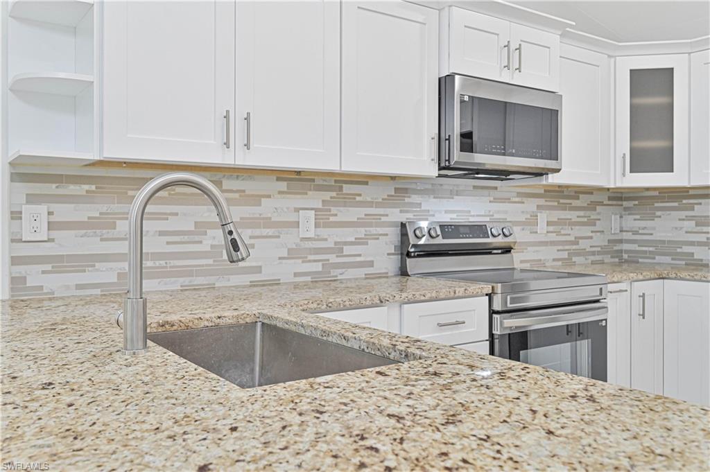 640 Lydia Street Lehigh Acres, FL 33974 - Photo 13 of 26 a kitchen with stainless steel appliances granite countertop a sink a stove a microwave and cabinets