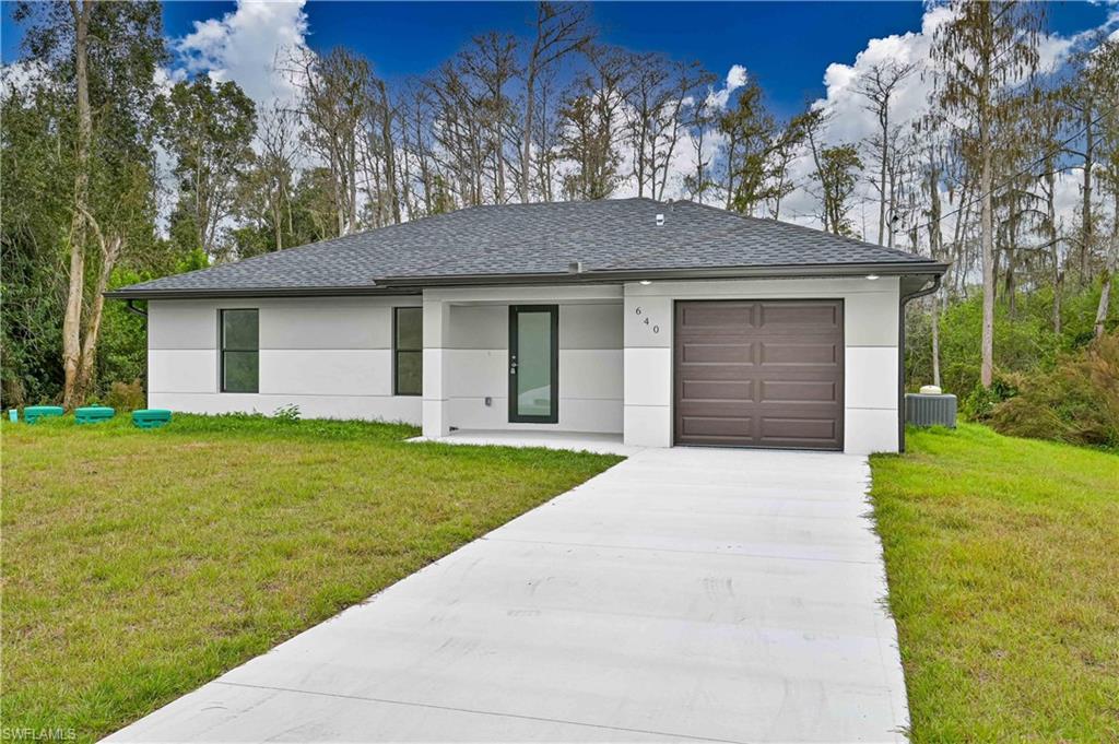 640 Lydia Street Lehigh Acres, FL 33974 - Photo 2 of 26 a front view of house with yard and trees in the background
