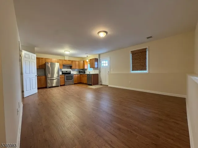 a view of empty room with wooden floor and window