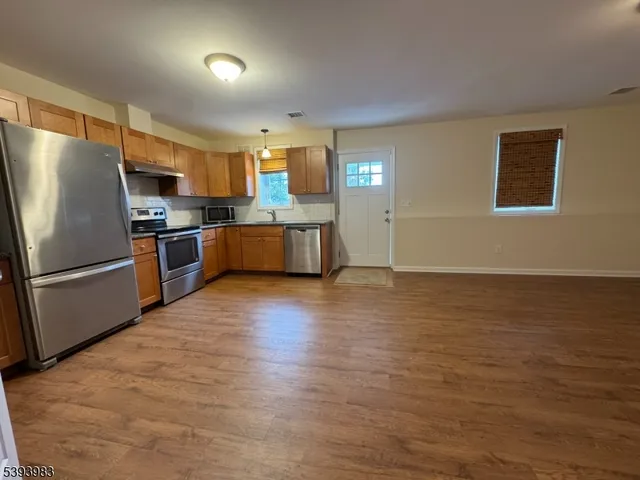 a kitchen with stainless steel appliances wooden floor and large window