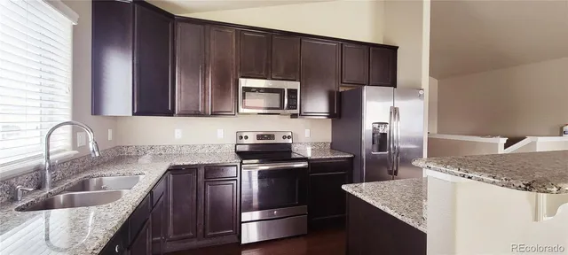 a kitchen with granite countertop wooden cabinets and stainless steel appliances