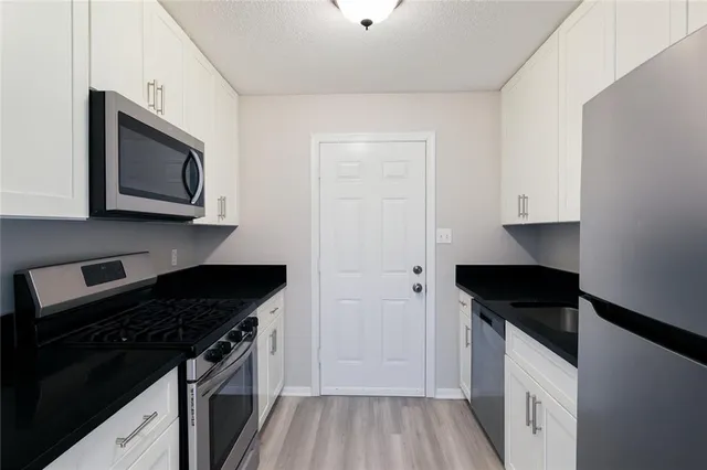 a kitchen with stainless steel appliances granite countertop white cabinets and black stove top oven with granite countertops