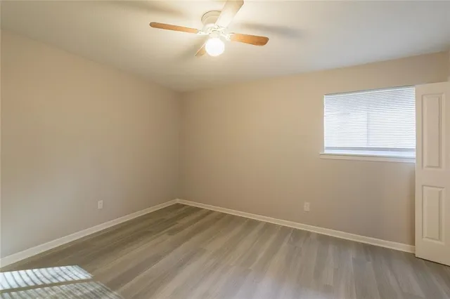 an empty room with a window and ceiling fan