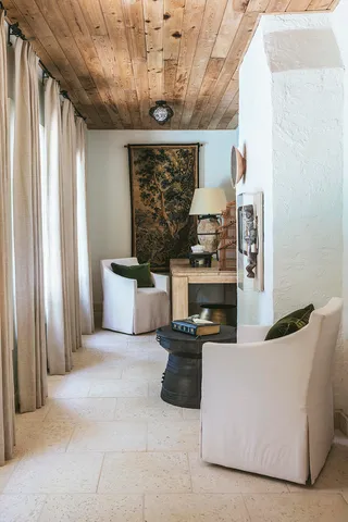 a living room with couches and a fireplace with kitchen view