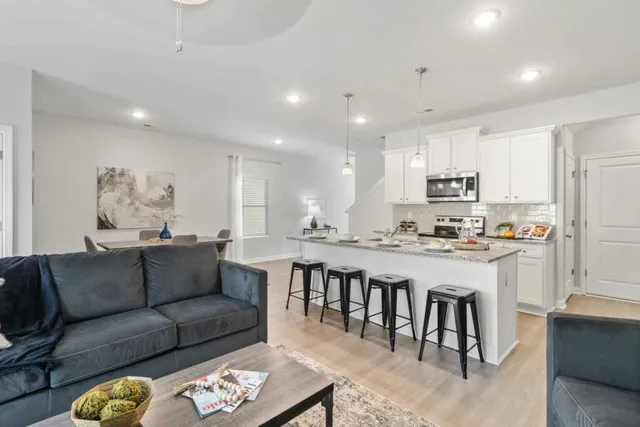 a living room with stainless steel appliances kitchen island granite countertop a couch and cabinets