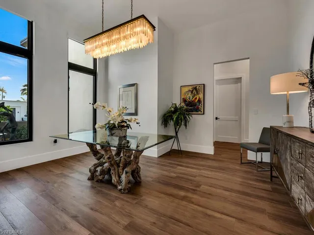 a dining room with wooden floor a glass table and chairs