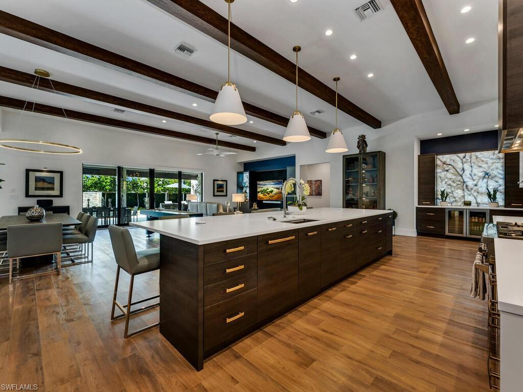 1251 Creech Road Naples, FL 34103 - Photo 6 of 44 a living room with stainless steel appliances kitchen island granite countertop lots of wooden cabinets a dining table and chairs