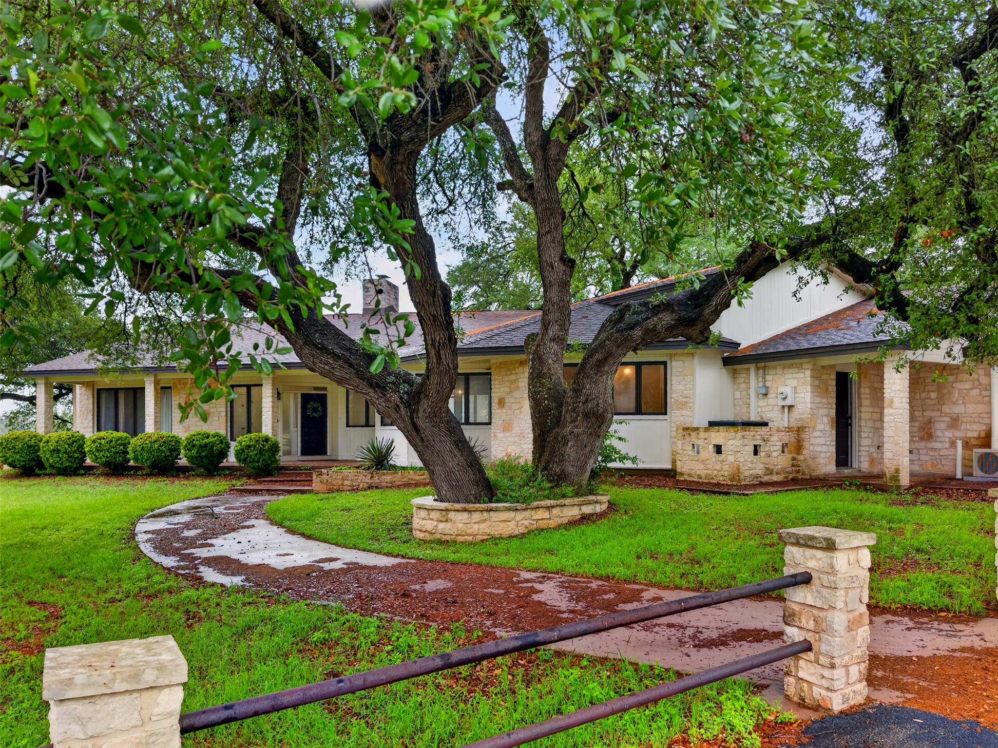 The property features a stone facade, a covered front porch, and a well-maintained lawn with mature trees