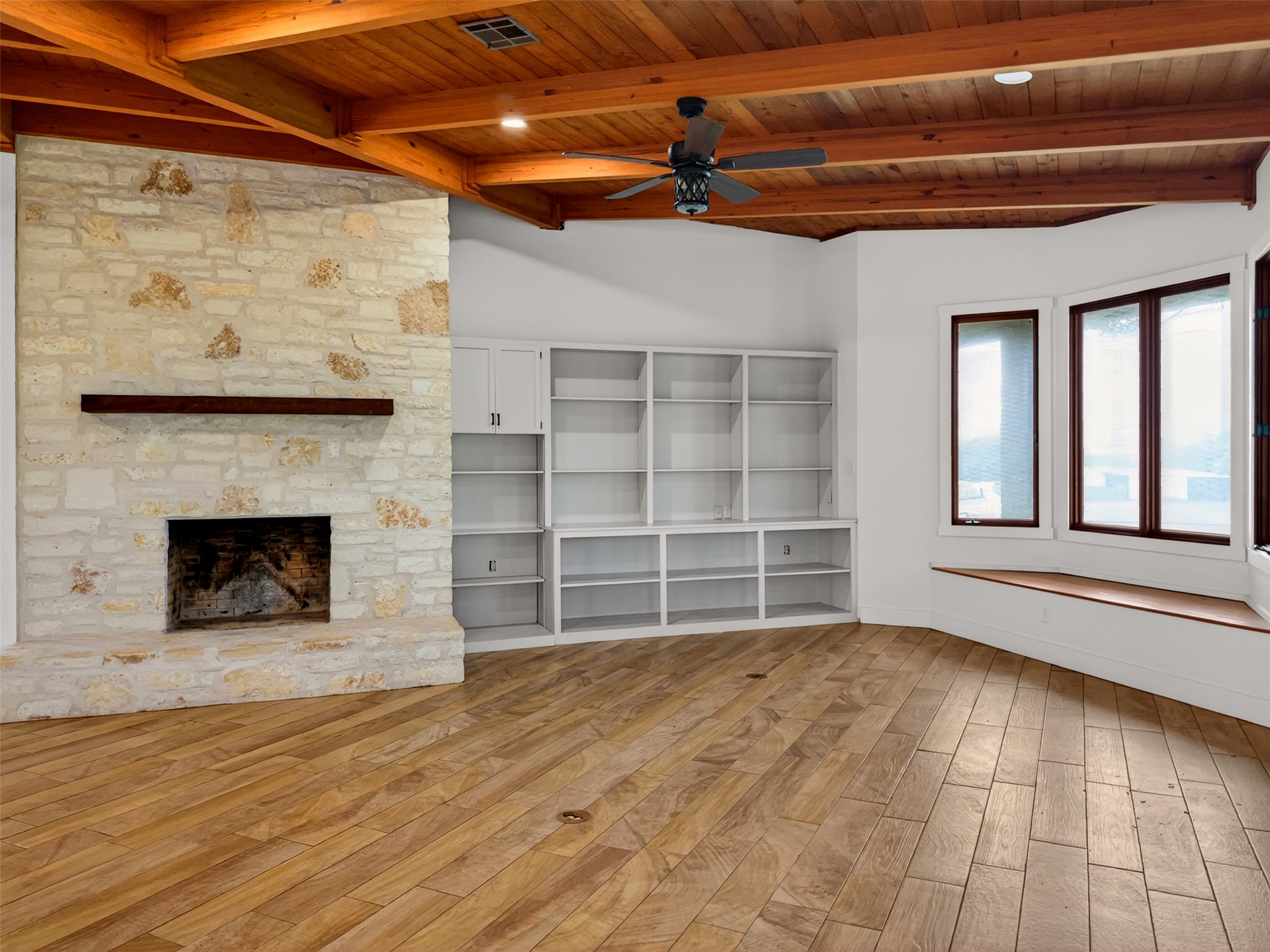 6106 Southeast Fm Ranch Buckholts, TX 76518 - Photo 11 of 38 The living space features a stone fireplace with a wooden mantel, built-in shelving, and a bay window with a built-in window seat