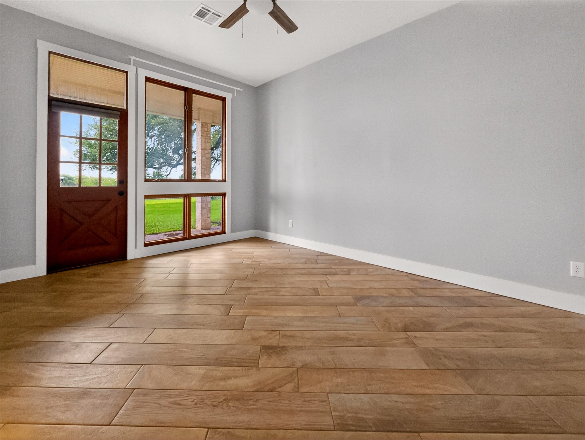6106 Southeast Fm Ranch Buckholts, TX 76518 - Photo 14 of 38 Room featuring light wood-look tile flooring, light gray walls, a ceiling fan, and large windows with views of a green outdoor area