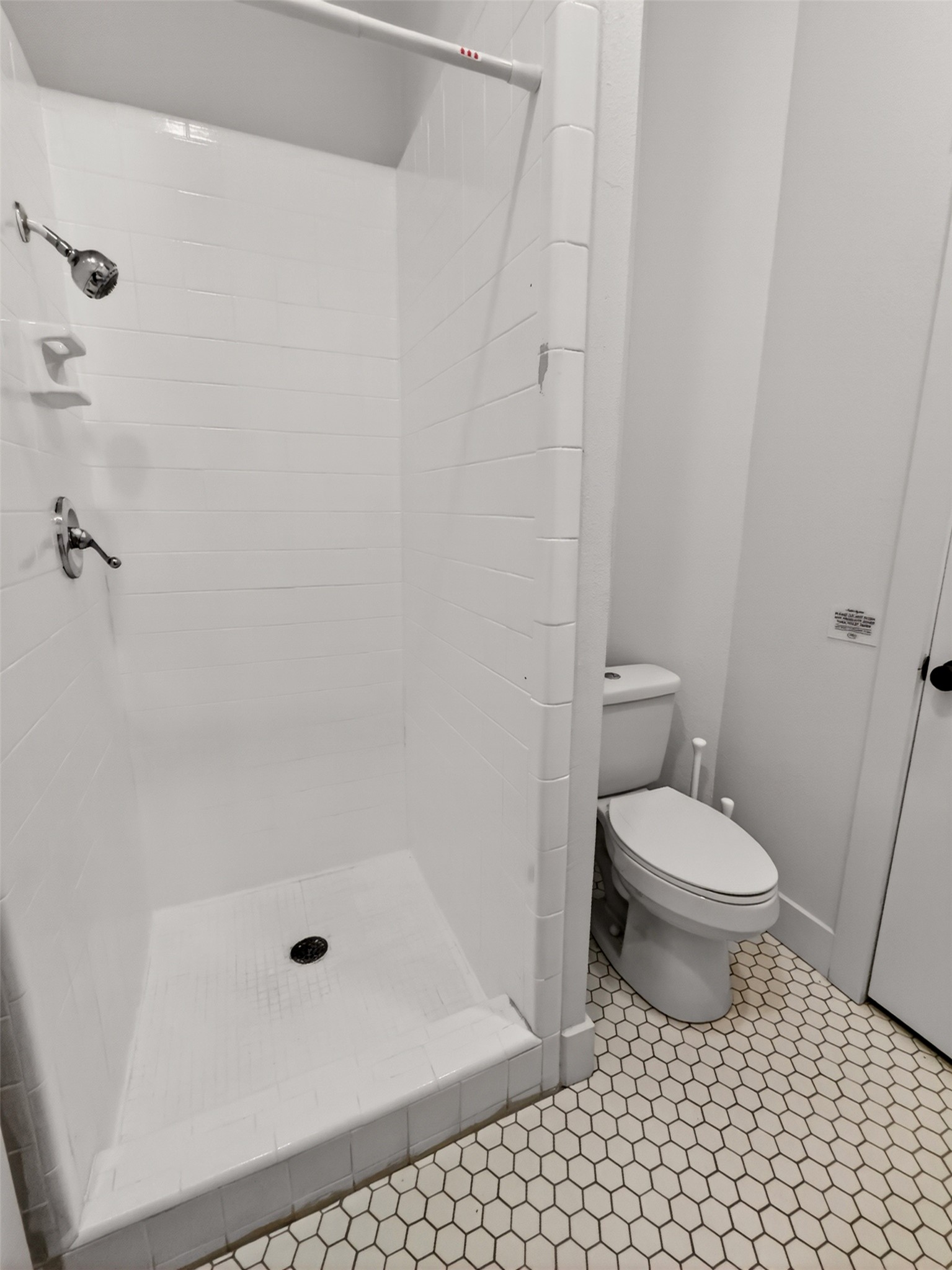6106 Southeast Fm Ranch Buckholts, TX 76518 - Photo 16 of 38 The bathroom features a walk-in shower with a chrome showerhead and control, a white toilet, and hexagonal tile flooring