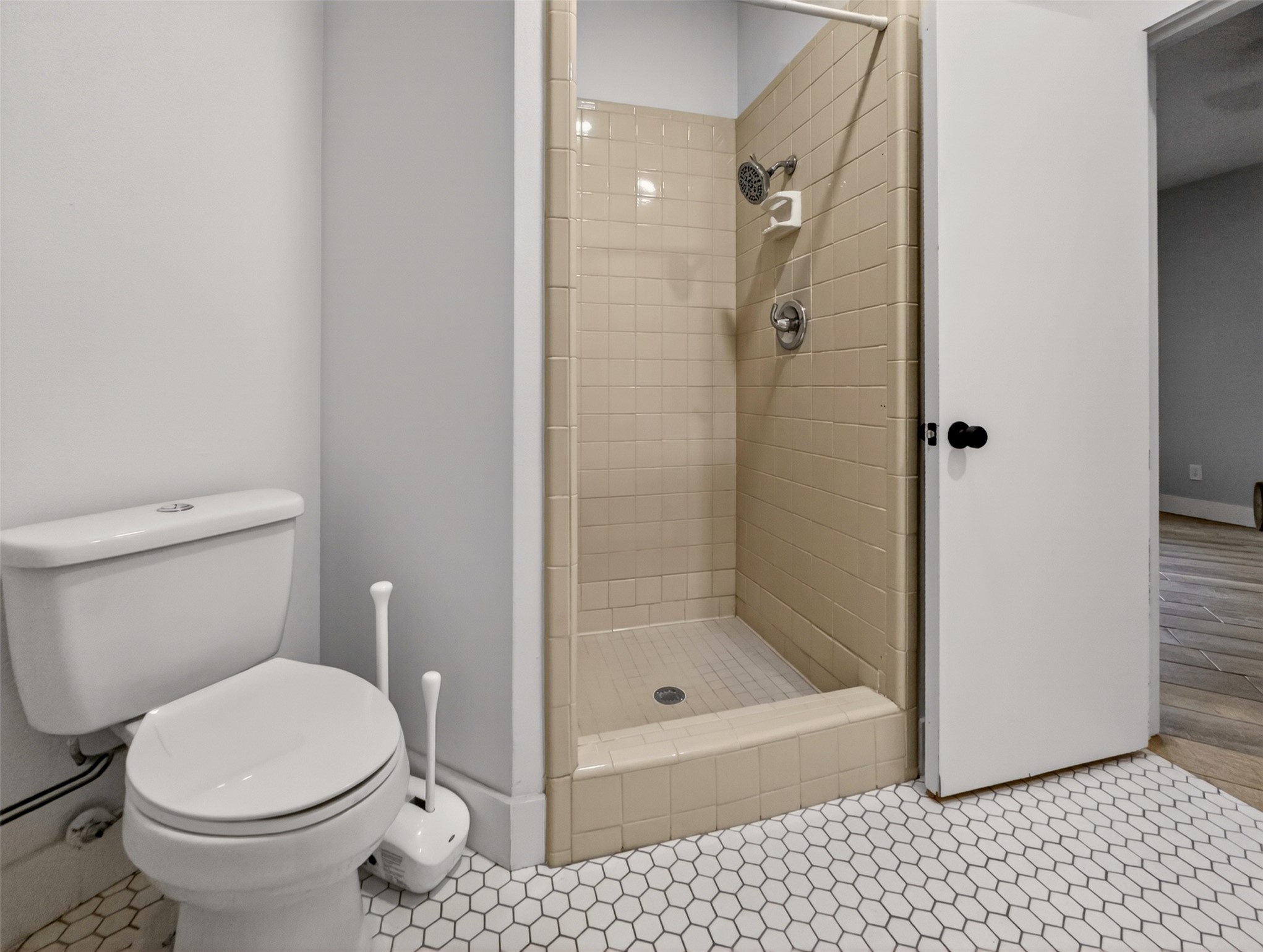 6106 Southeast Fm Ranch Buckholts, TX 76518 - Photo 18 of 38 Bathroom featuring a white toilet, a shower with neutral-toned tiled walls, and white hexagonal floor tiles