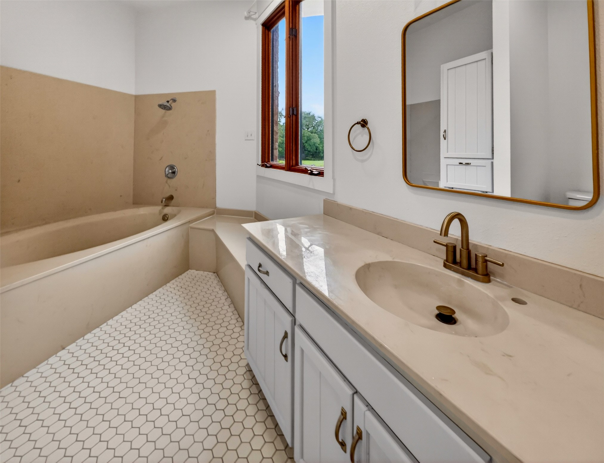 6106 Southeast Fm Ranch Buckholts, TX 76518 - Photo 22 of 38 Bathroom featuring a built-in bathtub with shower, hexagonal floor tiles, a vanity with a countertop and integrated sink, and a rectangular mirror with a gold frame