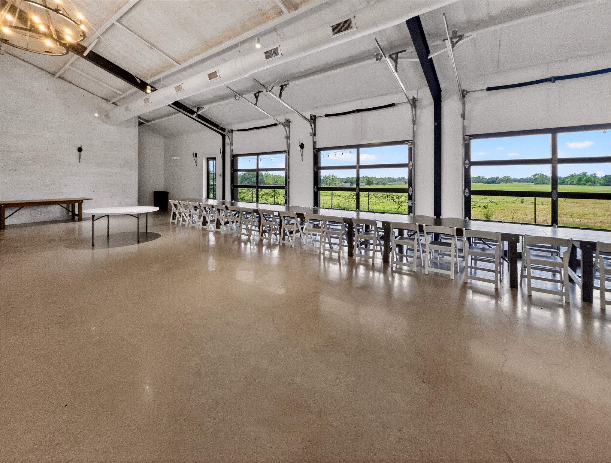 6106 Southeast Fm Ranch Buckholts, TX 76518 - Photo 30 of 38 Expansive interior space featuring concrete flooring, a high ceiling with exposed ductwork, and large glass paneled doors offering views of the surrounding green landscape