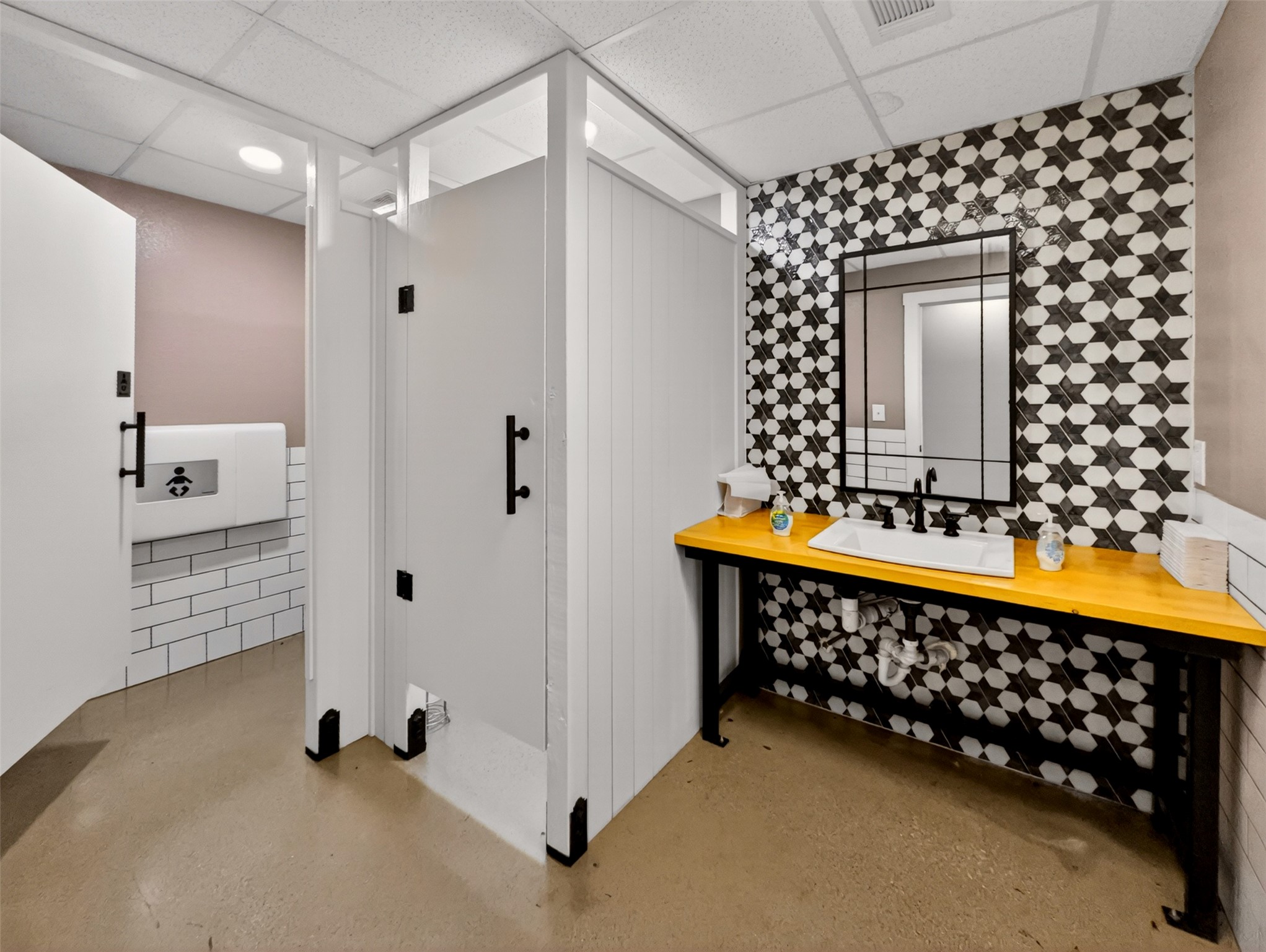 6106 Southeast Fm Ranch Buckholts, TX 76518 - Photo 34 of 38 Well-appointed washroom featuring a vanity with a rectangular basin, a black framed mirror, and a striking black and white patterned tile wall