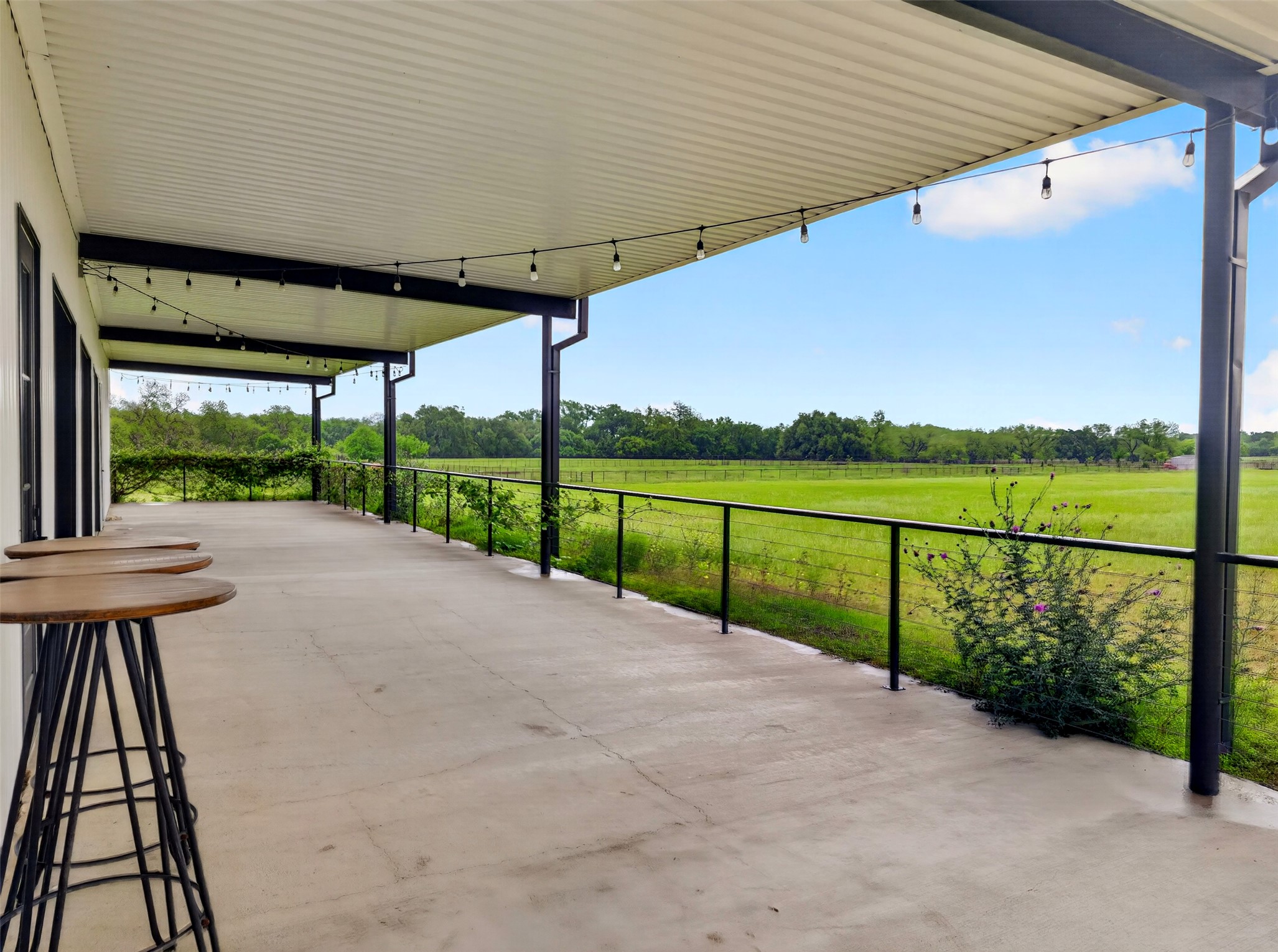 6106 Southeast Fm Ranch Buckholts, TX 76518 - Photo 36 of 38 Expansive covered patio with string lights, overlooking a large grassy area with distant trees
