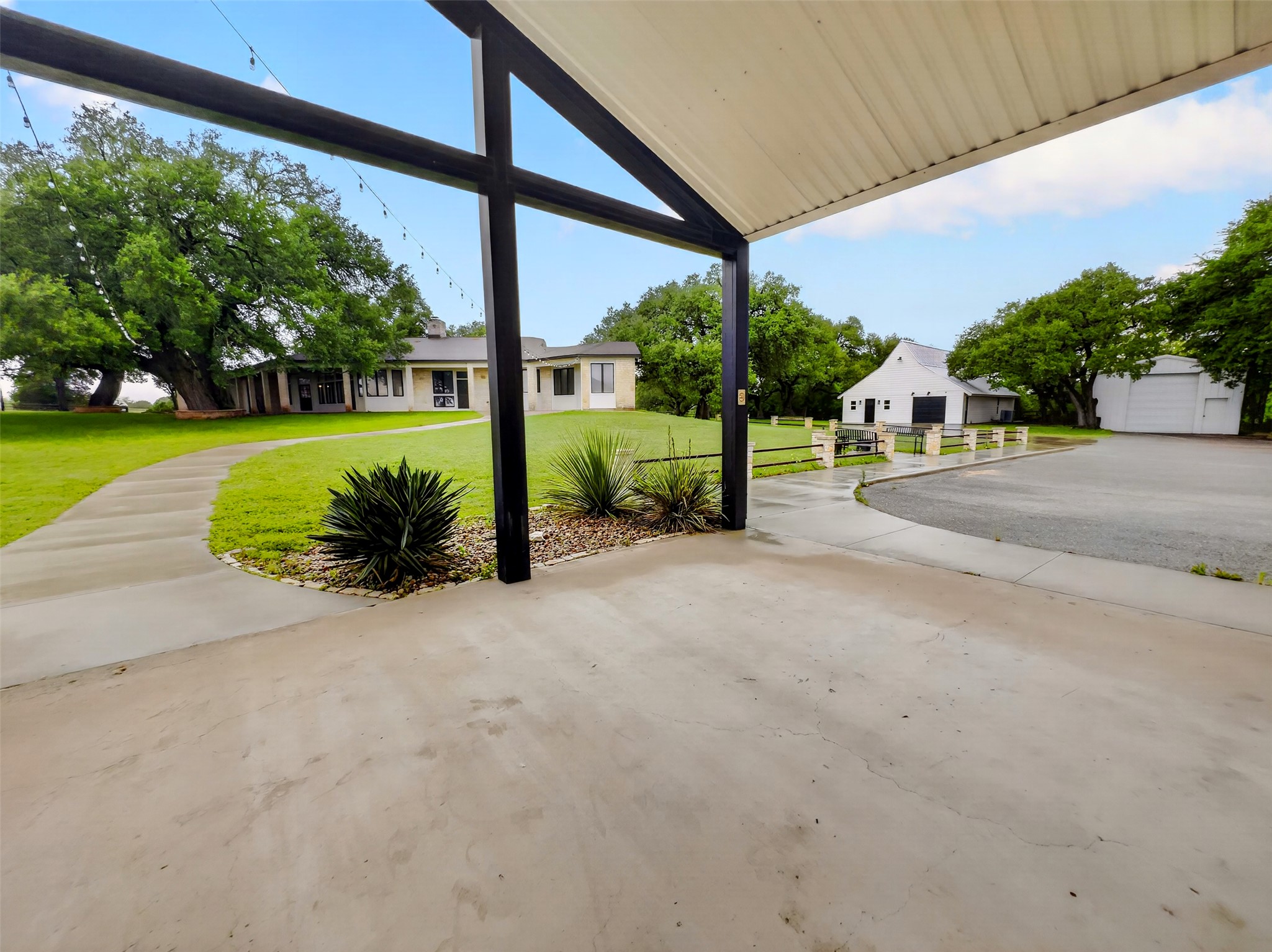 6106 Southeast Fm Ranch Buckholts, TX 76518 - Photo 37 of 38 The property features a concrete patio area with an overhead structure, a winding concrete pathway, and a large lawn with mature trees