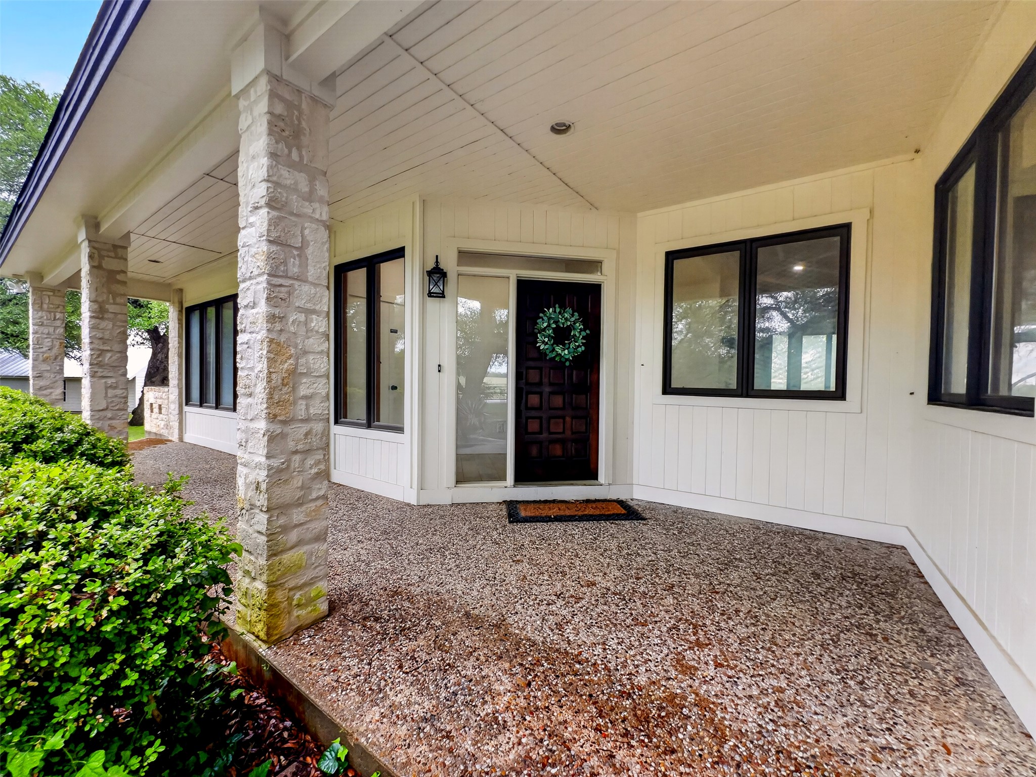 6106 Southeast Fm Ranch Buckholts, TX 76518 - Photo 4 of 38 The property features a covered porch with stone pillars, a textured aggregate surface, and a prominent dark wood front door