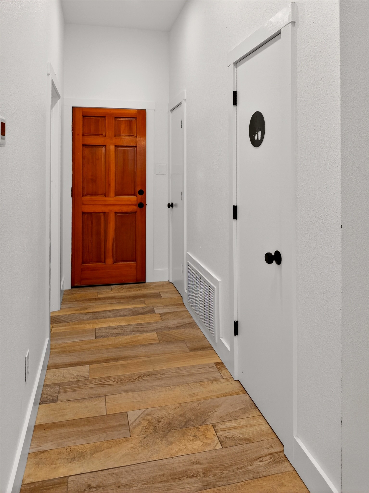 6106 Southeast Fm Ranch Buckholts, TX 76518 - Photo 6 of 38 The hallway features wood-look tile flooring, white walls, and a warm-toned wooden door with a panel design